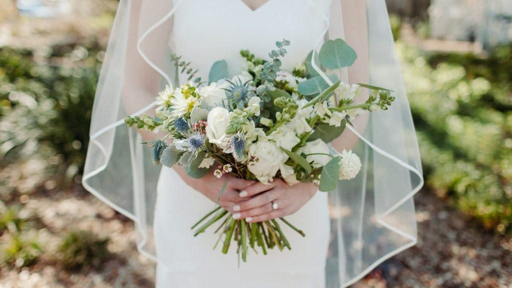 woman in white wedding dress holding white flower bouquet